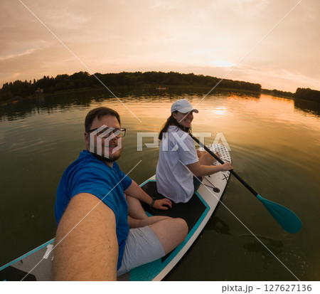 Couple Paddleboarding at Sunset 127627136