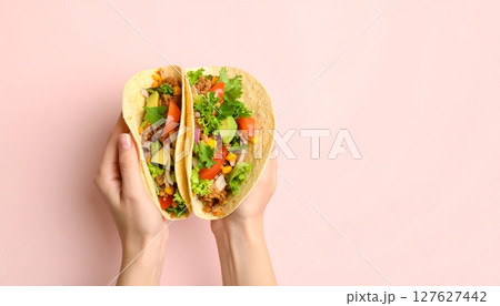 Hands holding colorful Easter eggs alongside a plate of fresh salad with green vegetables, tomatoes, and bruschetta 127627442