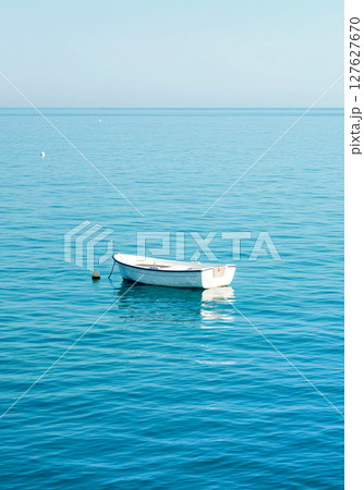 波のない静かな青い水面と、孤独に浮かぶ一艘の舟 波のない静かな青い水面と、孤独に浮かぶ一艘の舟 127627670