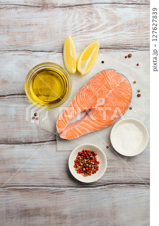 Fresh raw salmon steak with lemon, olive oil and spices on rustic wooden background. Ingredients for making healthy dinner. Healthy diet concept. Top view, copy space. Fresh raw salmon steak with lemon, olive oil and spices on rustic wooden background. Ingredients for making healthy dinner. Healthy diet concept. Top view, copy space. 127627839