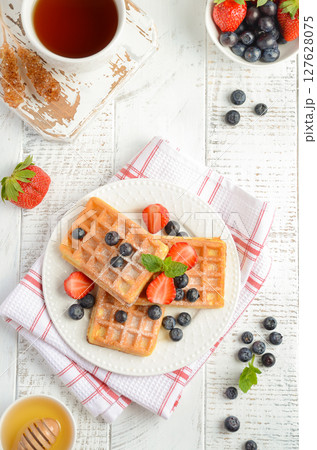 Waffles with fresh berries on rustic wooden background, top view Waffles with fresh berries on rustic wooden background, top view 127628075