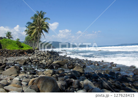 Waves Crashing Between the Rocks on the Beach in Sumatra, Lampung 127628415