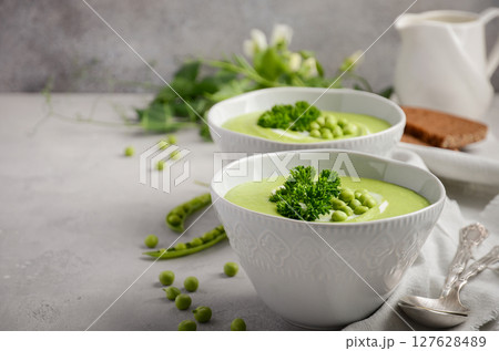 Green pea soup in bowls on grey concrete or stone background, selective focus 127628489
