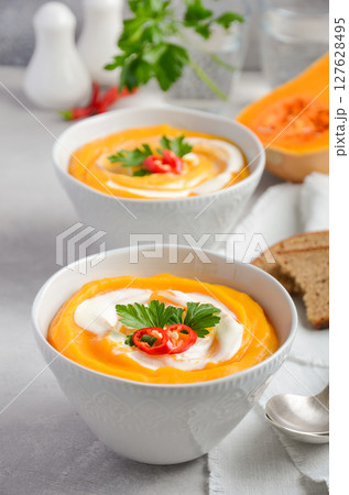Pumpkin soup with cream and parsley on a grey concrete or stone background, selective focus Pumpkin soup with cream and parsley on a grey concrete or stone background, selective focus 127628495