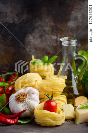 Pasta, vegetables, herbs and spices for Italian food on the wooden background, selective focus, copy space. 127628501