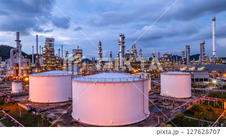 Oil refinery petrochemical plant at dusk illuminated storage tank industrial infrastructure, Oil refinery petrochemical product storage tank at oil refinery factory industry, Global energy refinery. Oil refinery petrochemical plant at dusk illuminated storage tank industrial infrastructure, Oil refinery petrochemical product storage tank at oil refinery factory industry, Global energy refinery. 127628707