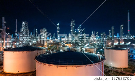 Oil refinery petrochemical plant at dusk illuminated storage tank industrial infrastructure, Oil refinery petrochemical product storage tank at oil refinery factory industry, Global energy refinery. 127628709