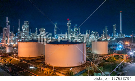 Oil refinery petrochemical plant at night illuminated storage tank industrial infrastructure, Oil refinery petrochemical product storage tank at oil refinery factory industry, Global energy refinery. Oil refinery petrochemical plant at night illuminated storage tank industrial infrastructure, Oil refinery petrochemical product storage tank at oil refinery factory industry, Global energy refinery. 127628794