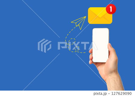 A hand is displaying a smartphone with a notification indicating a new message 127629090