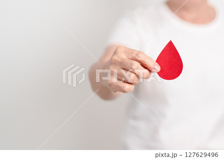 Elderly woman with red Blood drop paper for concept of June World Blood Donor day, Donation, April Hemophilia awareness day, May Thalassemia Day, Anemia awareness, June Sickle Cell and Blood Disorders Elderly woman with red Blood drop paper for concept of June World Blood Donor day, Donation, April Hemophilia awareness day, May Thalassemia Day, Anemia awareness, June Sickle Cell and Blood Disorders 127629496