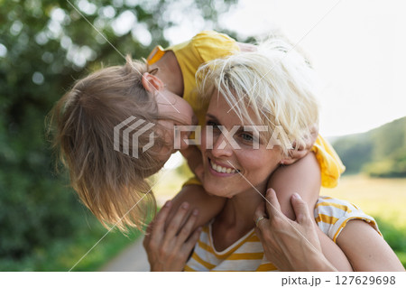 A portrait of mother carrying little girl on shoulders. A portrait of mother carrying little girl on shoulders. 127629698