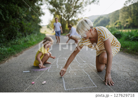 Mom and girl drawing with chalk on road. . Mom and girl drawing with chalk on road. . 127629718