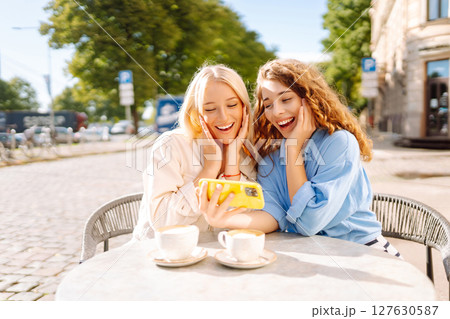 Young women enjoying in coffee and having fun with smartphone. Coffee break after shopping. Young women enjoying in coffee and having fun with smartphone. Coffee break after shopping. 127630587