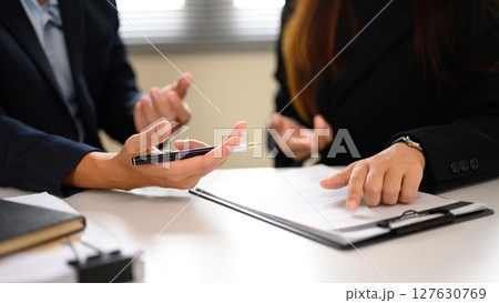 Close up of businesspeople in discussion while reviewing and preparing to sign a contract document. 127630769