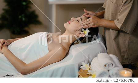 Young woman receiving relaxing head massage in spa, eyes closed and peaceful expression Young woman receiving relaxing head massage in spa, eyes closed and peaceful expression 127630790