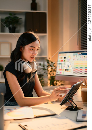 Female graphic designer working on digital tablet at modern desk with color palette on screen Female graphic designer working on digital tablet at modern desk with color palette on screen 127630817