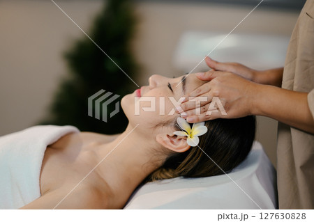 Young woman enjoying a calming head massage with eyes closed in a tranquil spa Young woman enjoying a calming head massage with eyes closed in a tranquil spa 127630828