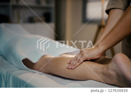 Therapist gently massaging client leg to promote circulation and relaxation Therapist gently massaging client leg to promote circulation and relaxation 127630830