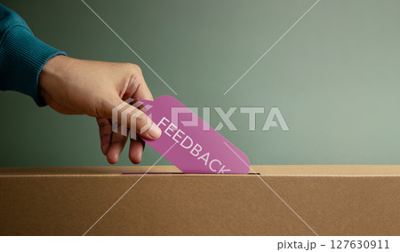 Hand putting feedback card in box symbolizing customer review, survey response, and constructive evaluation 127630911