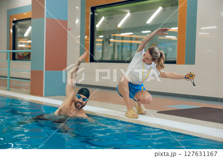 Young man having a workout with a female coach in the pool Young man having a workout with a female coach in the pool 127631167