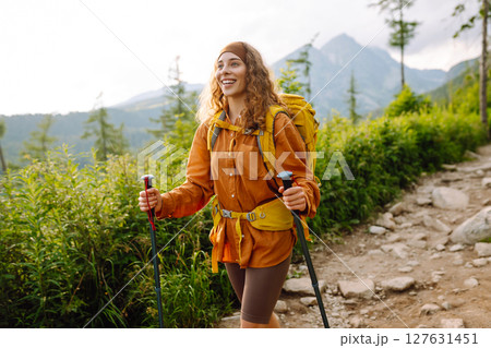Young woman traveler hiking poles on trail among the mountains. Hiking. Active lifestyle. 127631451
