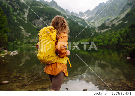 Travel Slovakia, Europe. Tourist with a yellow backpack stands against the backdrop of alpine lake. 127631471