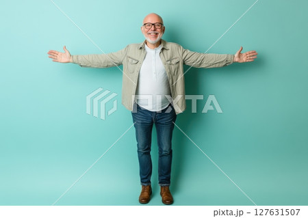 full length portrait of happy senior man with arms raised on green 127631507