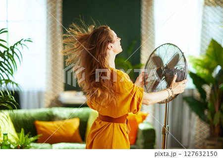 Woman Enjoying Fan Breeze on a Hot Summer Day 127632150