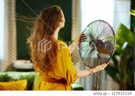Woman Adjusting Fan for Summer Cooling 127632154