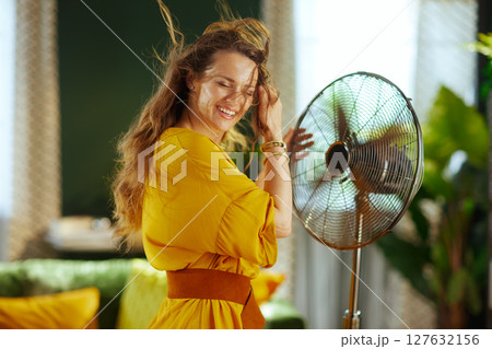 Woman Joyfully Embracing Fan\'s Cool Air 127632156