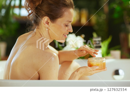 Woman Pampering Skin with Body Scrub in Bath 127632554