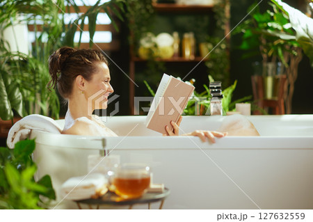 Woman Relaxing in Bubble Bath with Book 127632559