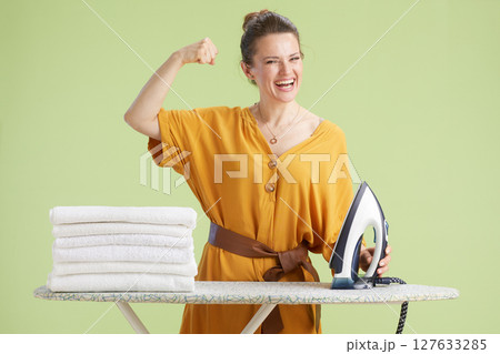 Joyful woman flexing arm in front of laundry 127633285