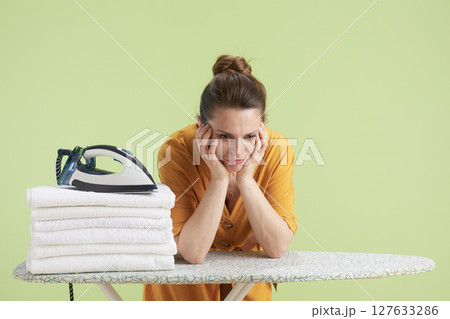 Tired woman leaning on hands beside laundry 127633286