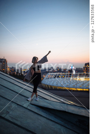 Beautiful woman on rooftop posing at sunset. Woman enjoys atmosphere of city of freedom. Relaxation. Beautiful woman on rooftop posing at sunset. Woman enjoys atmosphere of city of freedom. Relaxation. 127633568