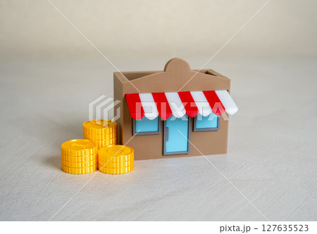 A store and a stack of money coins. Commercial real estate. Start your own business. A store and a stack of money coins. Commercial real estate. Start your own business. 127635523