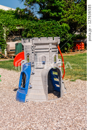 Colorful plastic playground with castle structure on gravel. Outdoor recreation, children's fun zone, and imaginative play environment concept. 127636585