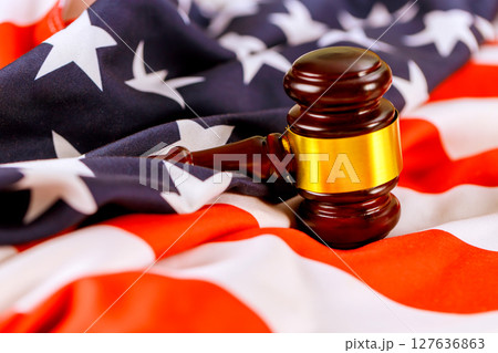 Justice gavel placed atop an American flag highlights importance of justice legal system in USA nation. Justice gavel placed atop an American flag highlights importance of justice legal system in USA nation. 127636863
