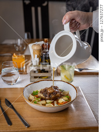Waiter pouring broth 127637277