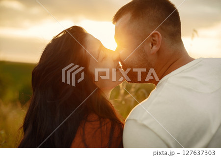 Couple in a field. Woman in a brown dress. Sunset background. 127637303