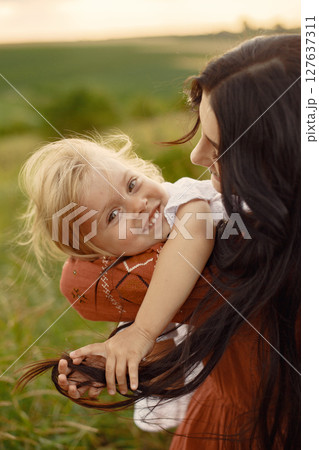 Family in a summer field. Mother in a brown dress. Cute little girl. Family in a summer field. Mother in a brown dress. Cute little girl. 127637311