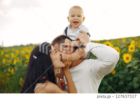Photo of happy family. Parents and daughter. Family together in sunflower field. Man in a white shirt. Photo of happy family. Parents and daughter. Family together in sunflower field. Man in a white shirt. 127637317