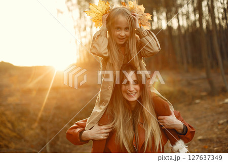 Fashionable mother with daughter. Family in a autumn park. Little daughter in a brown coat. 127637349