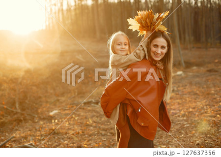 Fashionable mother with daughter. Family in a autumn park. Little daughter in a brown coat. Fashionable mother with daughter. Family in a autumn park. Little daughter in a brown coat. 127637356