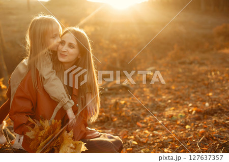 Fashionable mother with daughter. Family in a autumn park. Little daughter in a brown coat. 127637357