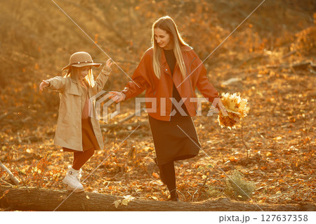 Fashionable mother with daughter. Family in a autumn park. Little daughter in a brown coat. Fashionable mother with daughter. Family in a autumn park. Little daughter in a brown coat. 127637358