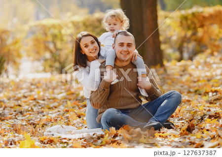 Family with cute little daughter. Father in a brown sweater. Family in a autumn field 127637387