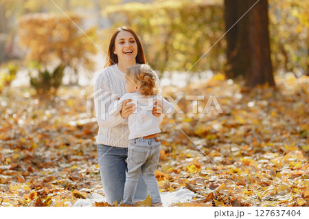 Fashionable mother with daughter. Family in a autumn park. Little girl in a white sweater. Fashionable mother with daughter. Family in a autumn park. Little girl in a white sweater. 127637404