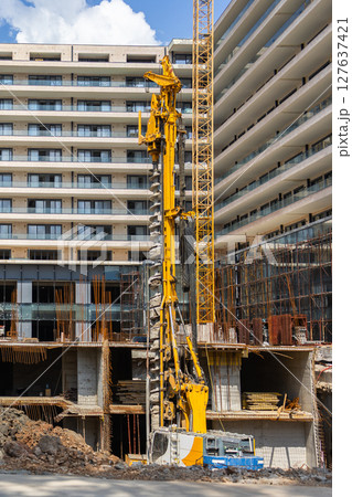 High-rise construction site in urban area. Modern development, civil engineering, and foundation work with industrial machinery. 127637421