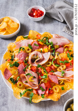 Snack trend Charcuterie nachos with potato chips on plate on table vertical view 127638512